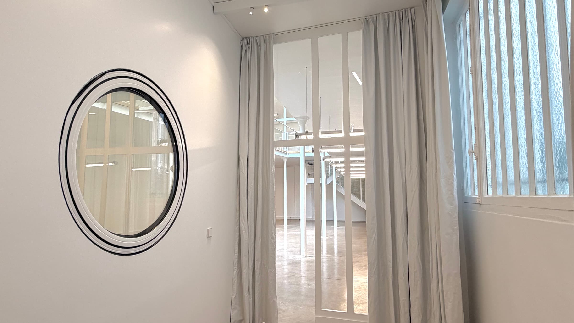 Pièce avec miroir hublot rond et porte verrière ouvrant sur le plateau