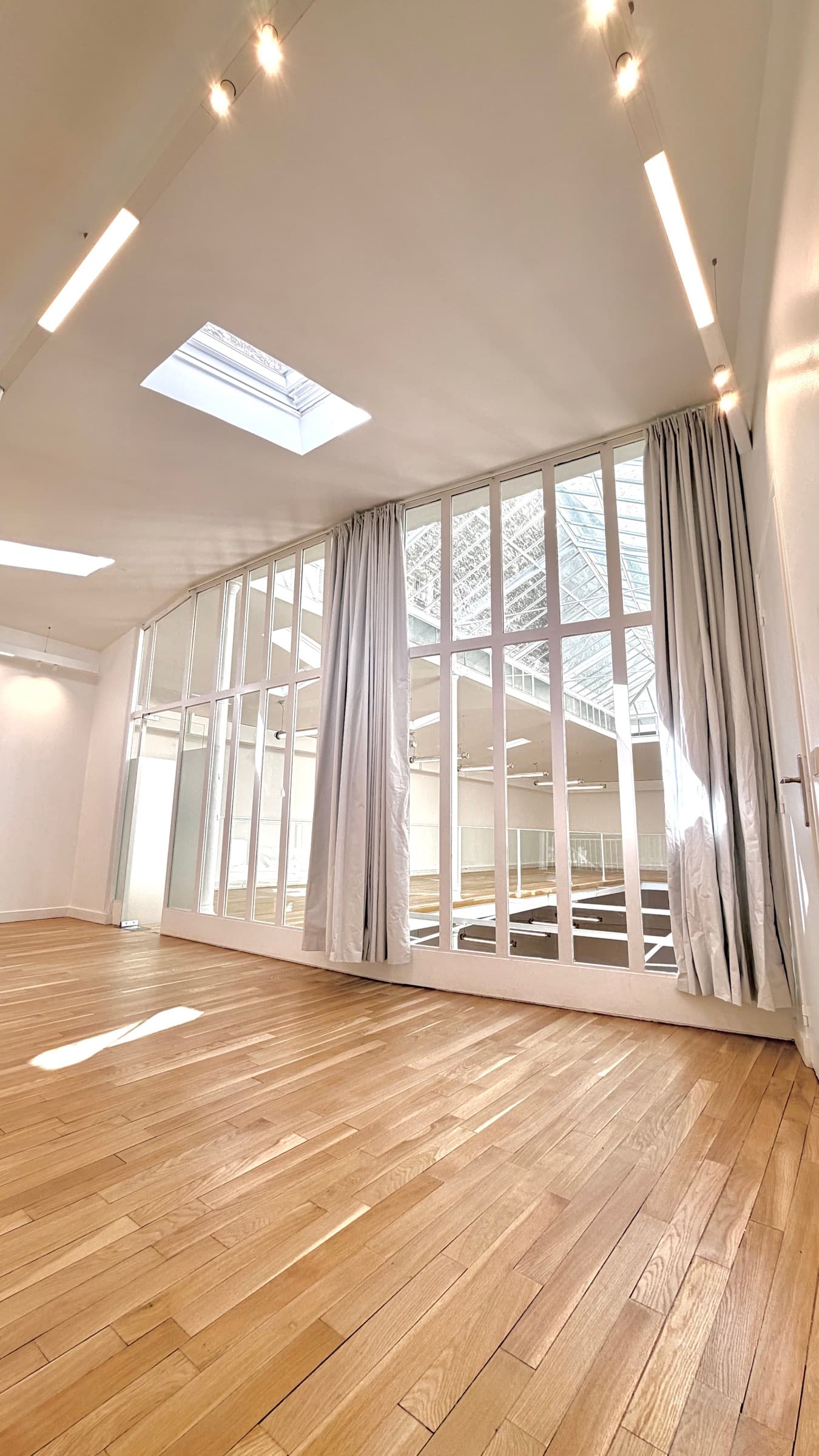 Bureau en parquet avec grande verrière intérieure ouvrant sur l'atrium et velux au plafond