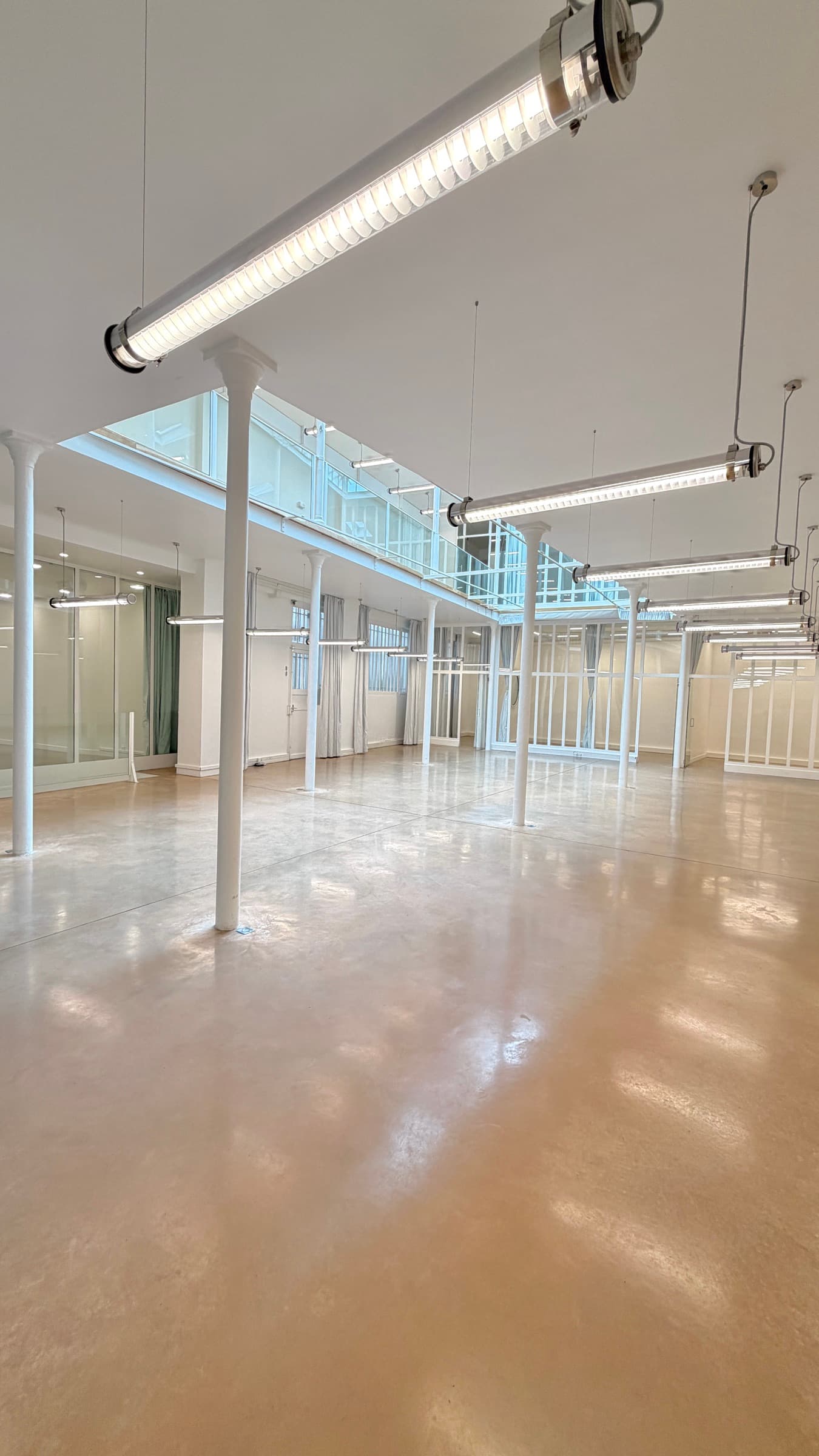 Grand angle du RDC avec luminaire tube au premier plan et mezzanine vitrée